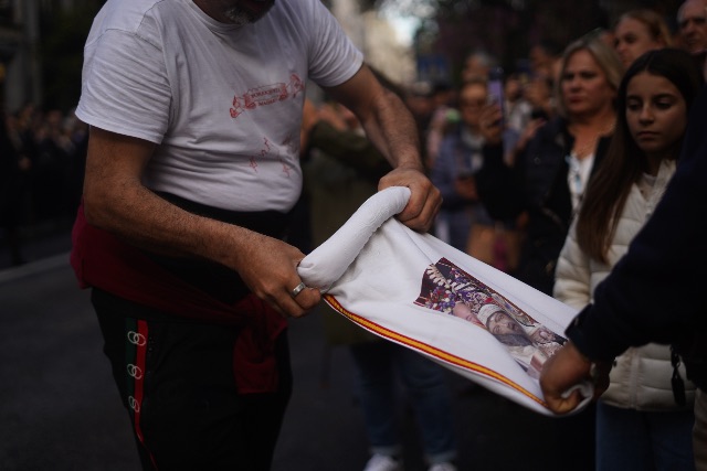 Participants in Madrid unfurling a printed religious canvas banner during a Semana Santa procession.