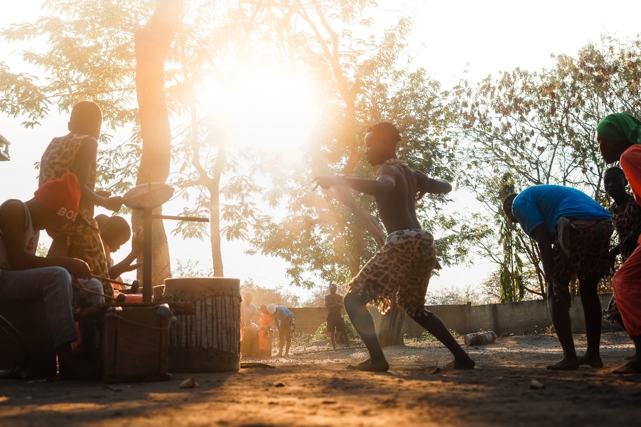 Silhouette of a Kandili Art Group performer in motion against a bright golden sunset.